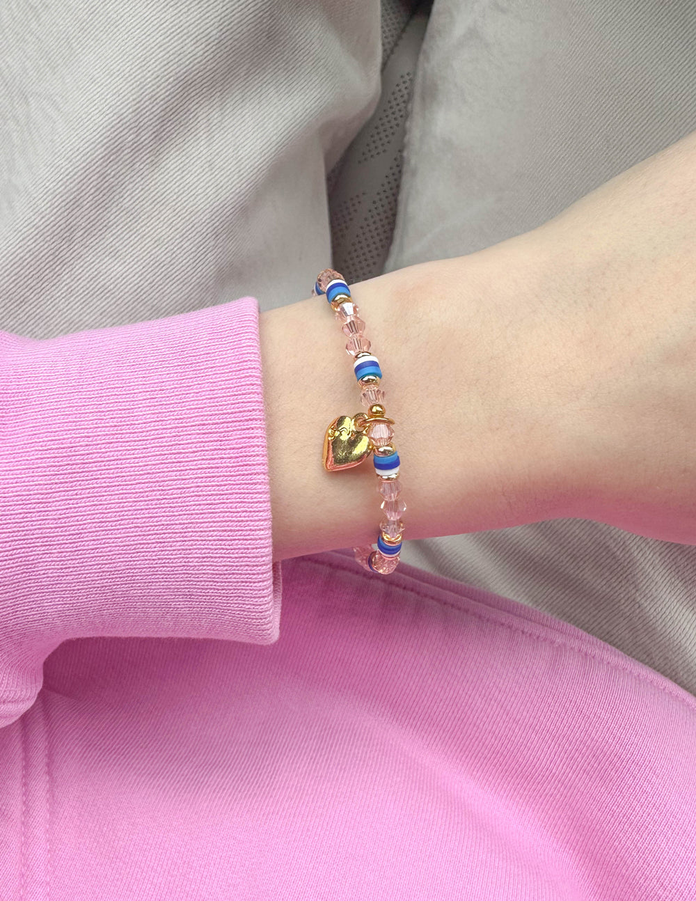 Heart charm beaded bracelet with blue accents and pink bead strand on wrist