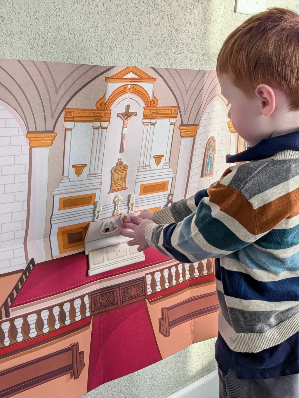 Child playing with church play story board, touching altar and candles