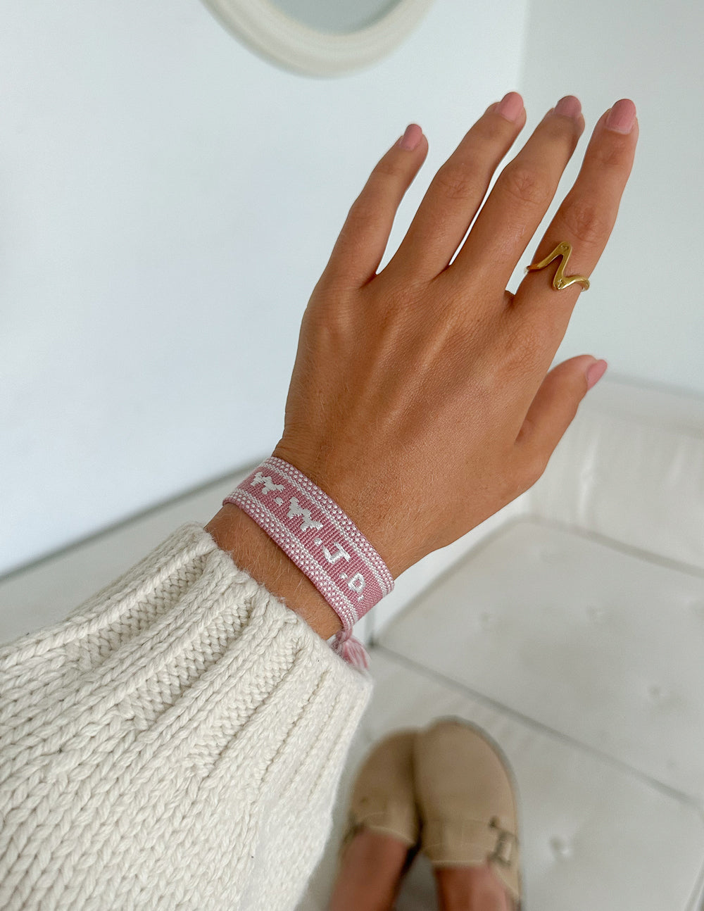 Pink embroidered bracelet on wrist with tassels at the ends