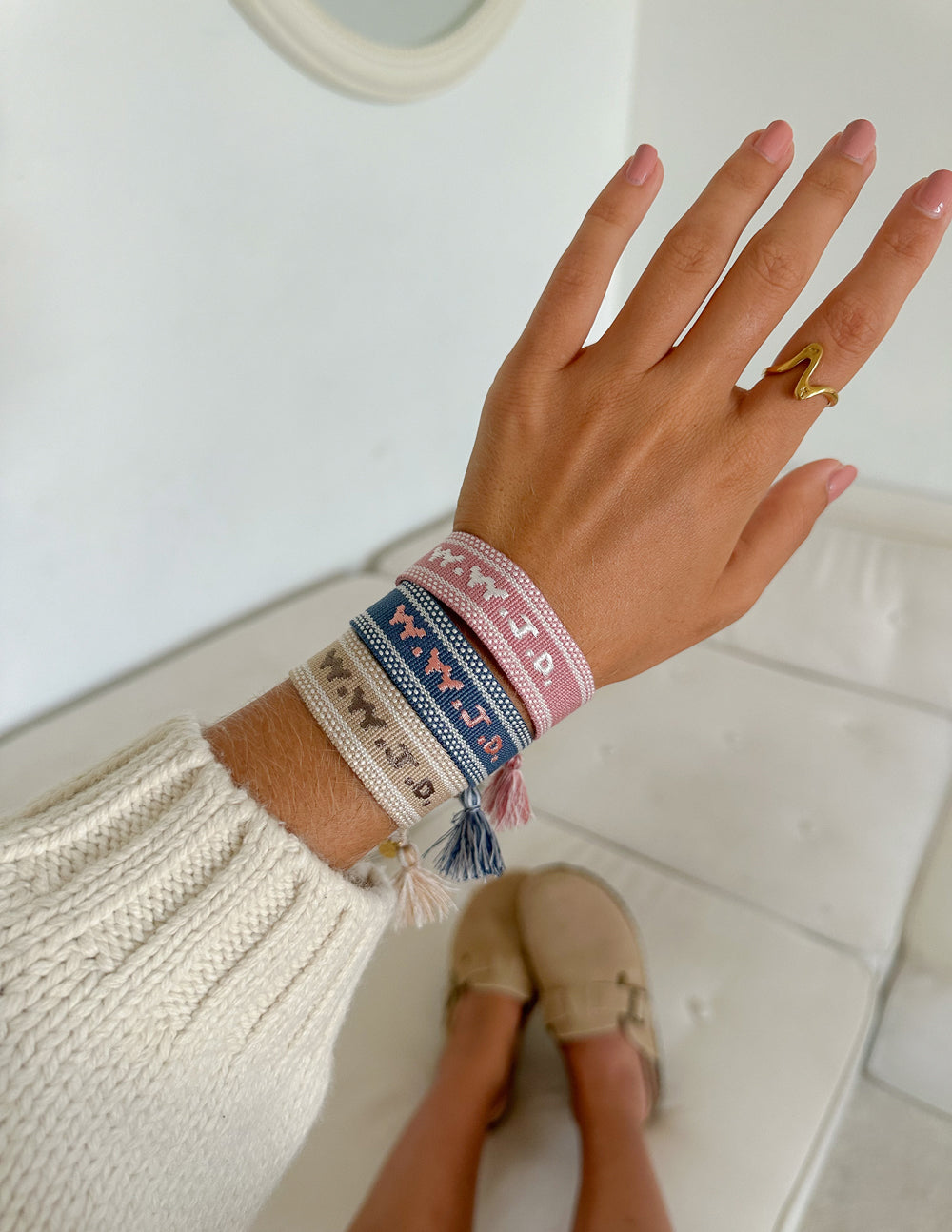 Pink and blue embroidered bracelet on wrist with tassels