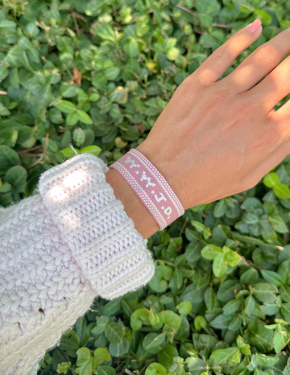 Pink embroidered bracelet with woven pattern, on a wrist