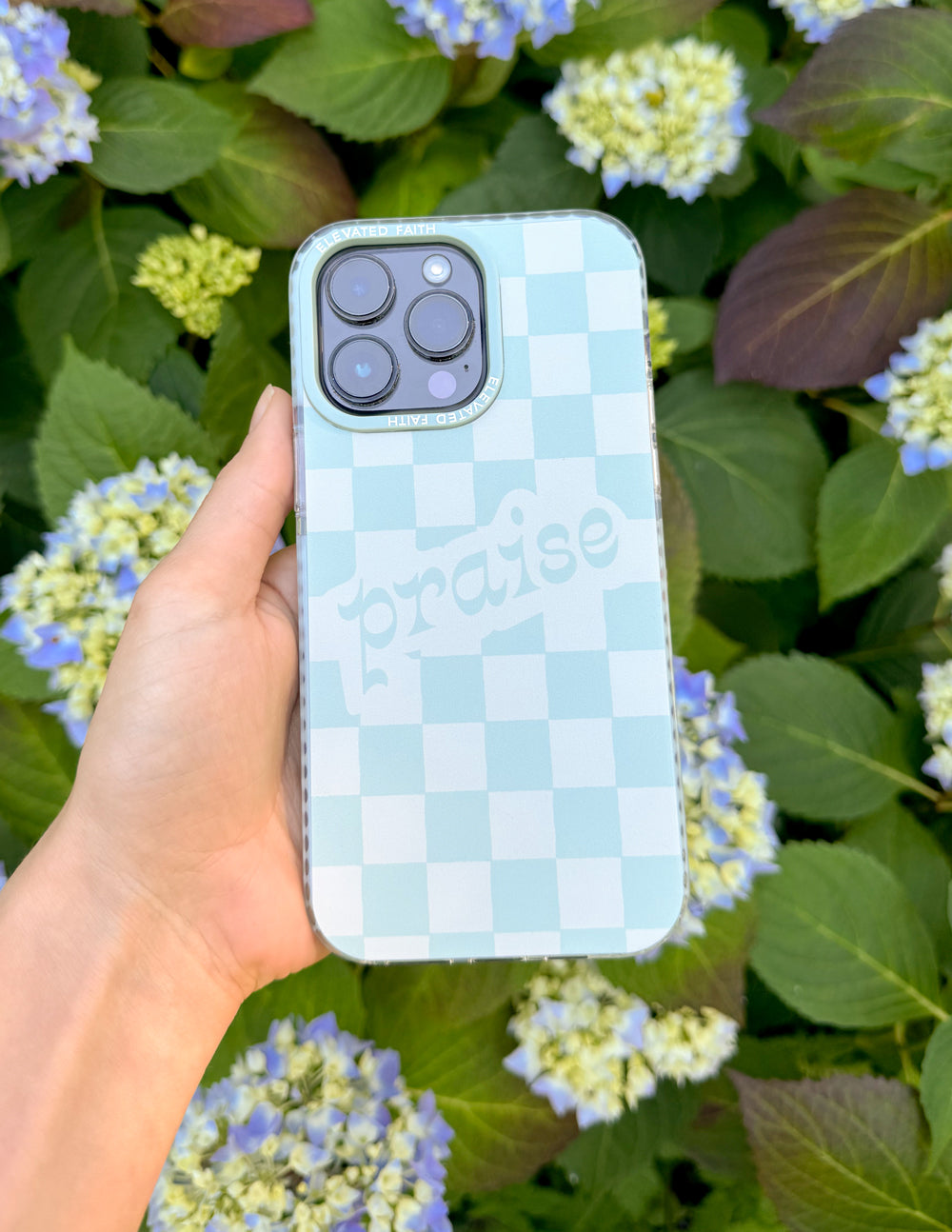 Light blue checkered phone case with camera cutouts and 'praise' text, held up