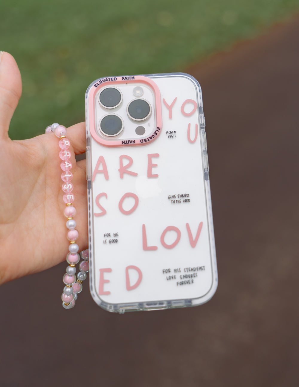 Clear phone case with pink lettering and four camera cutouts, with pink beaded strap