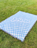 Light blue check throw blanket with fringe edges and 'praise' script design