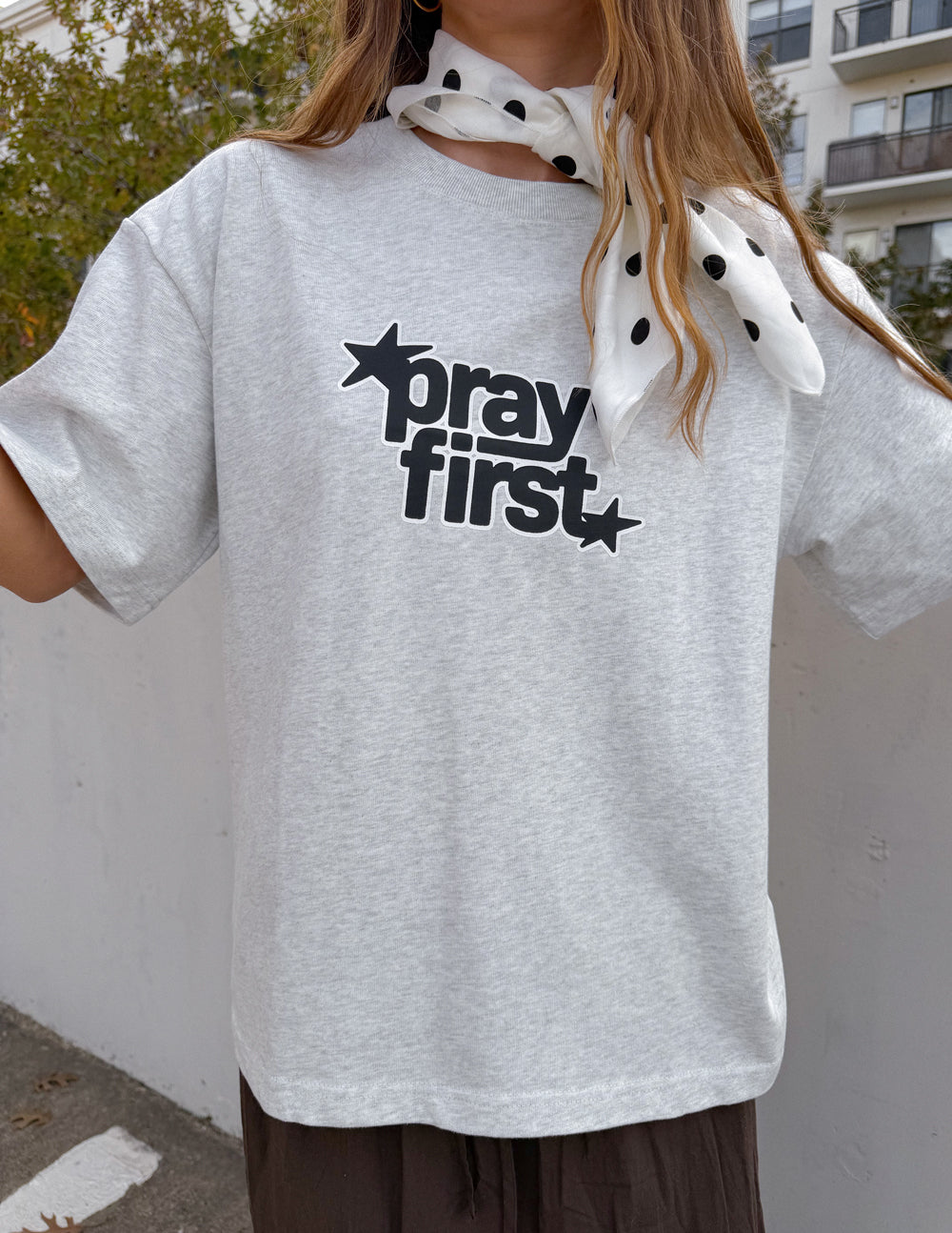 White heavyweight crewneck T-shirt with black “pray first” star graphic at center chest