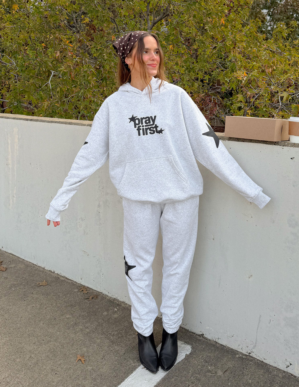 Light gray unisex hoodie with front kangaroo pocket and "pray first" chest graphic