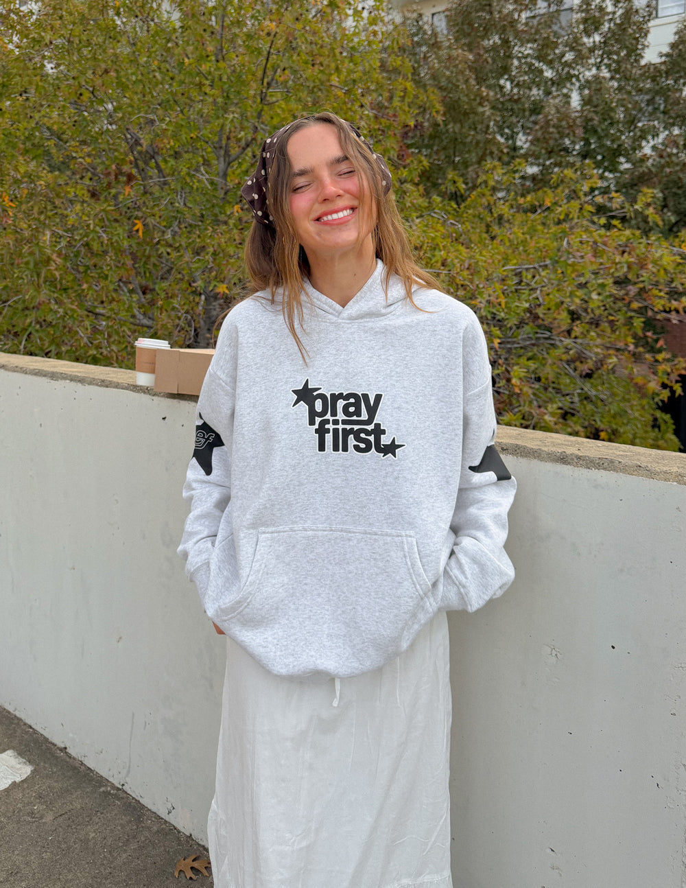 Light gray unisex hoodie with hood, "pray first" front logo, and kangaroo pocket
