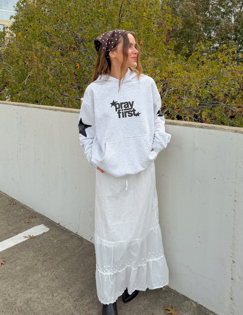 Light gray hoodie with "pray first" logo and star sleeve prints, relaxed fit