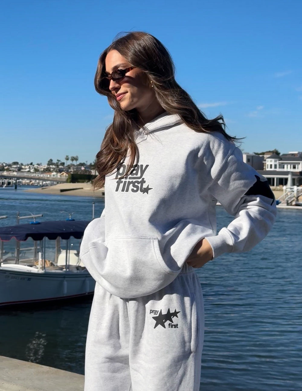 Light gray unisex hoodie, side view with hood and "pray first" logo on chest