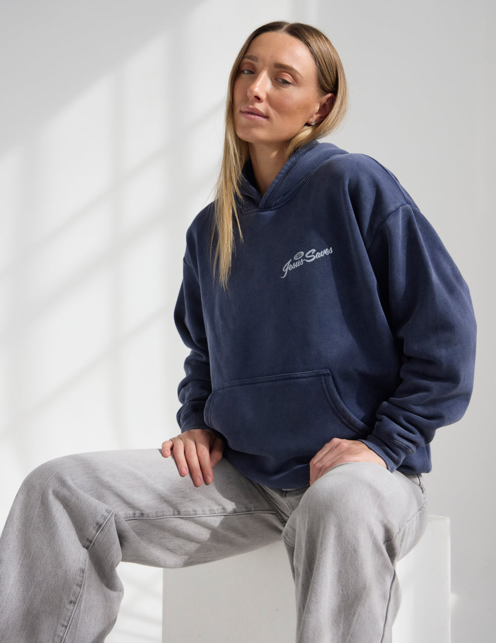 Dark navy unisex hoodie with hood and chest “Jesus Saves” logo, front view