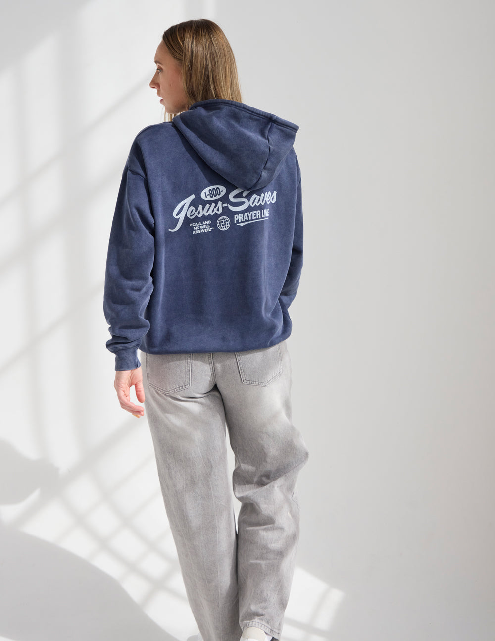Dark navy unisex hoodie worn from back with hood and “Jesus Saves Prayer Line” print
