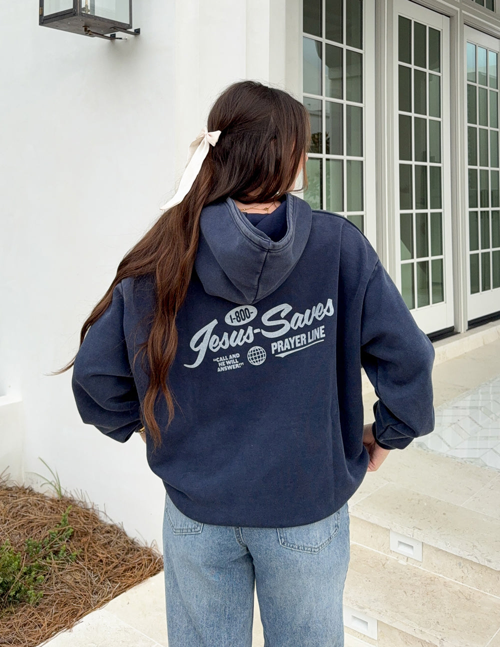 Dark navy unisex hoodie worn from back, with hood and “Jesus Saves Prayer Line” print