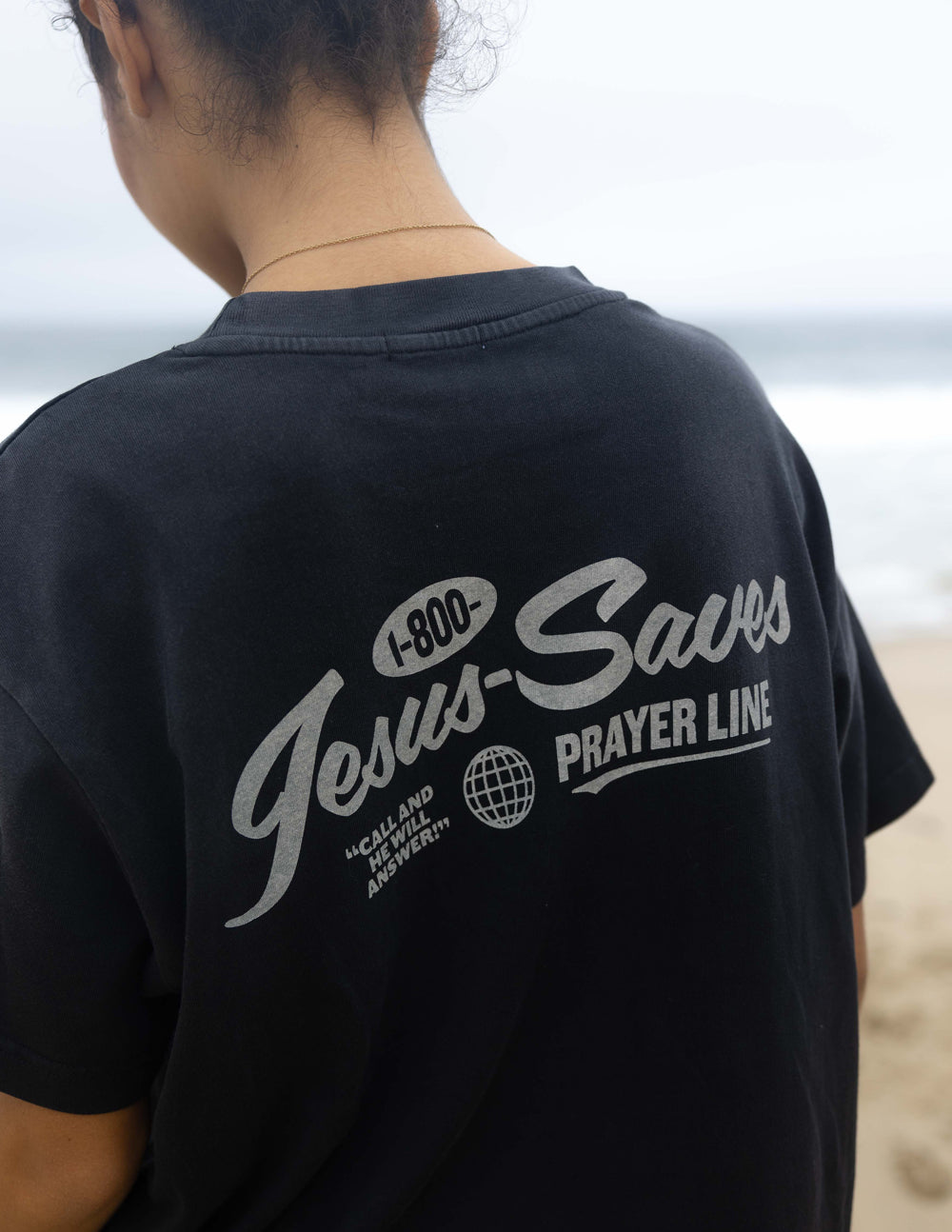 Black unisex T-shirt back close-up of 'Jesus Saves' logo and globe mark