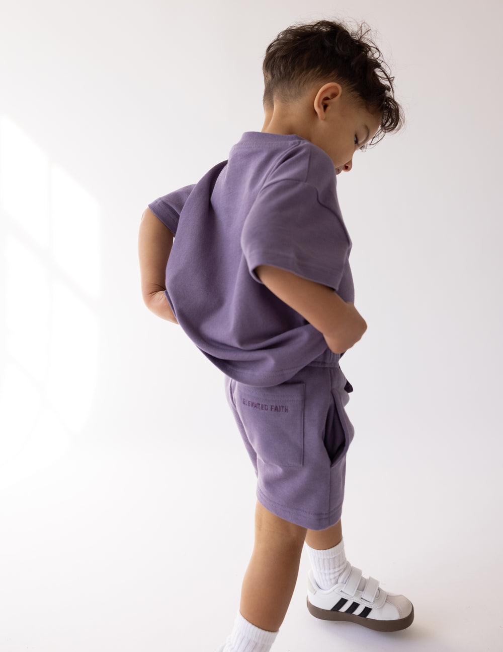 Kids purple shorts, back view with logo on lower left leg
