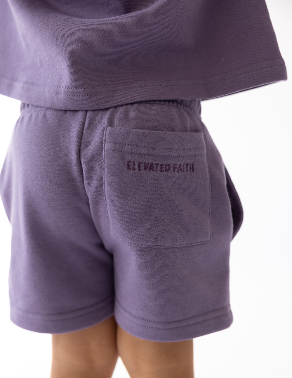 Kids purple shorts with “ELEVATED FAITH” logo on back pocket