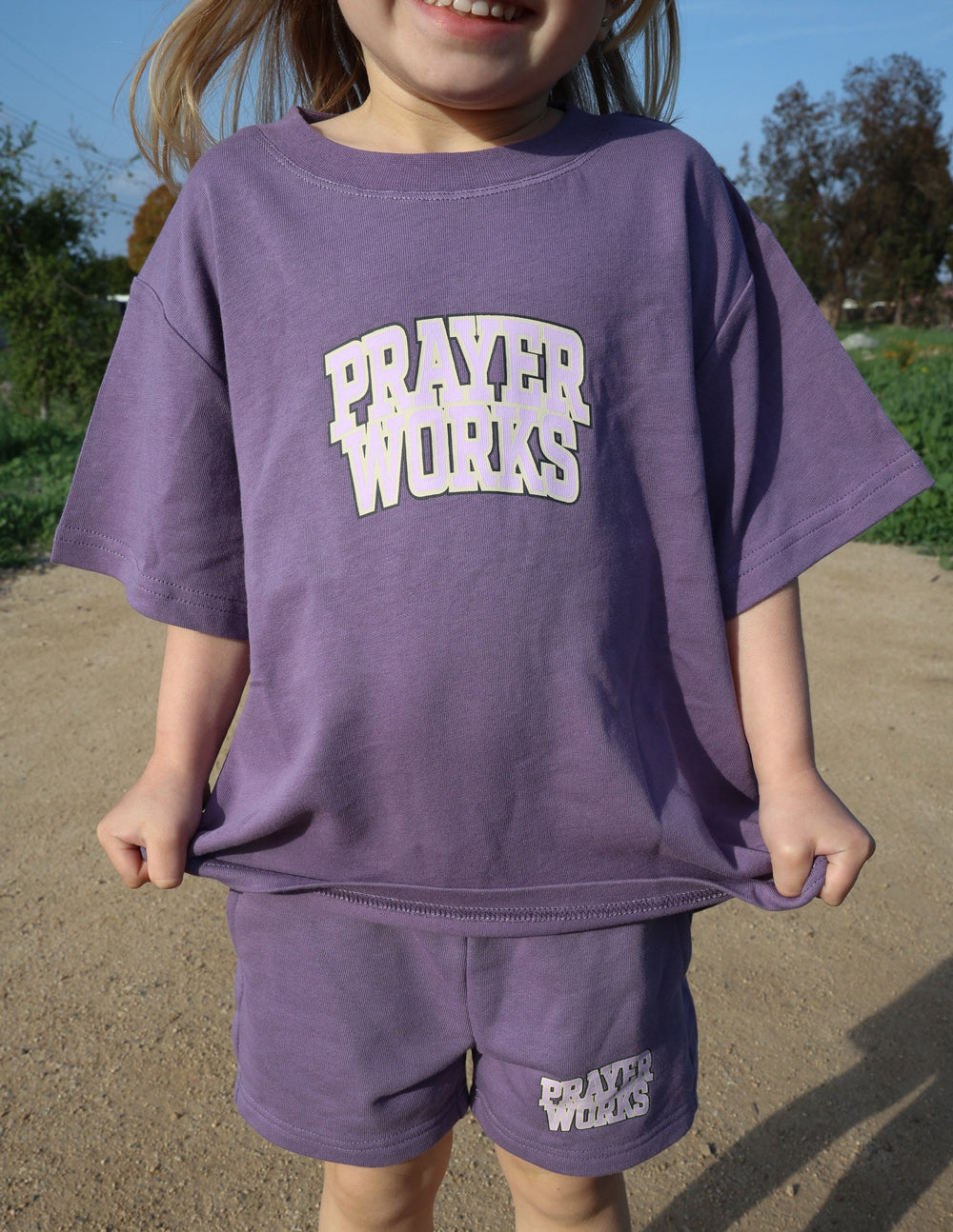 Kids purple T-shirt with 'PRAYER WORKS' logo print on front, loose fit