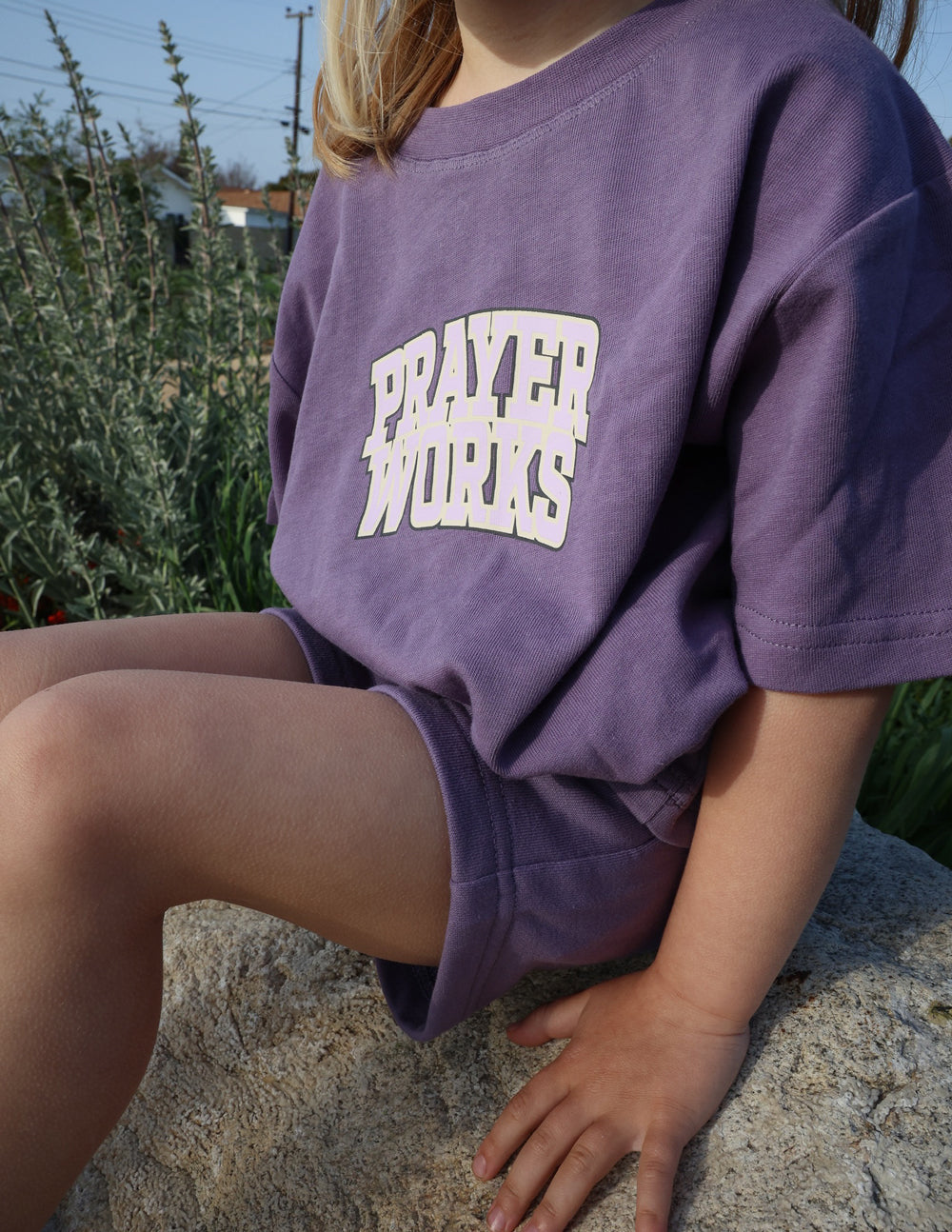 Kids purple T-shirt close-up with 'PRAYER WORKS' chest graphic