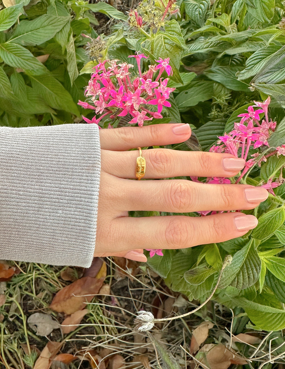 Gold band ring with engraved center detail on finger