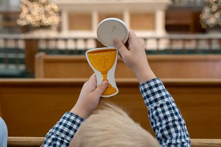 Catholic mass toy chalice and host pieces held up by hands