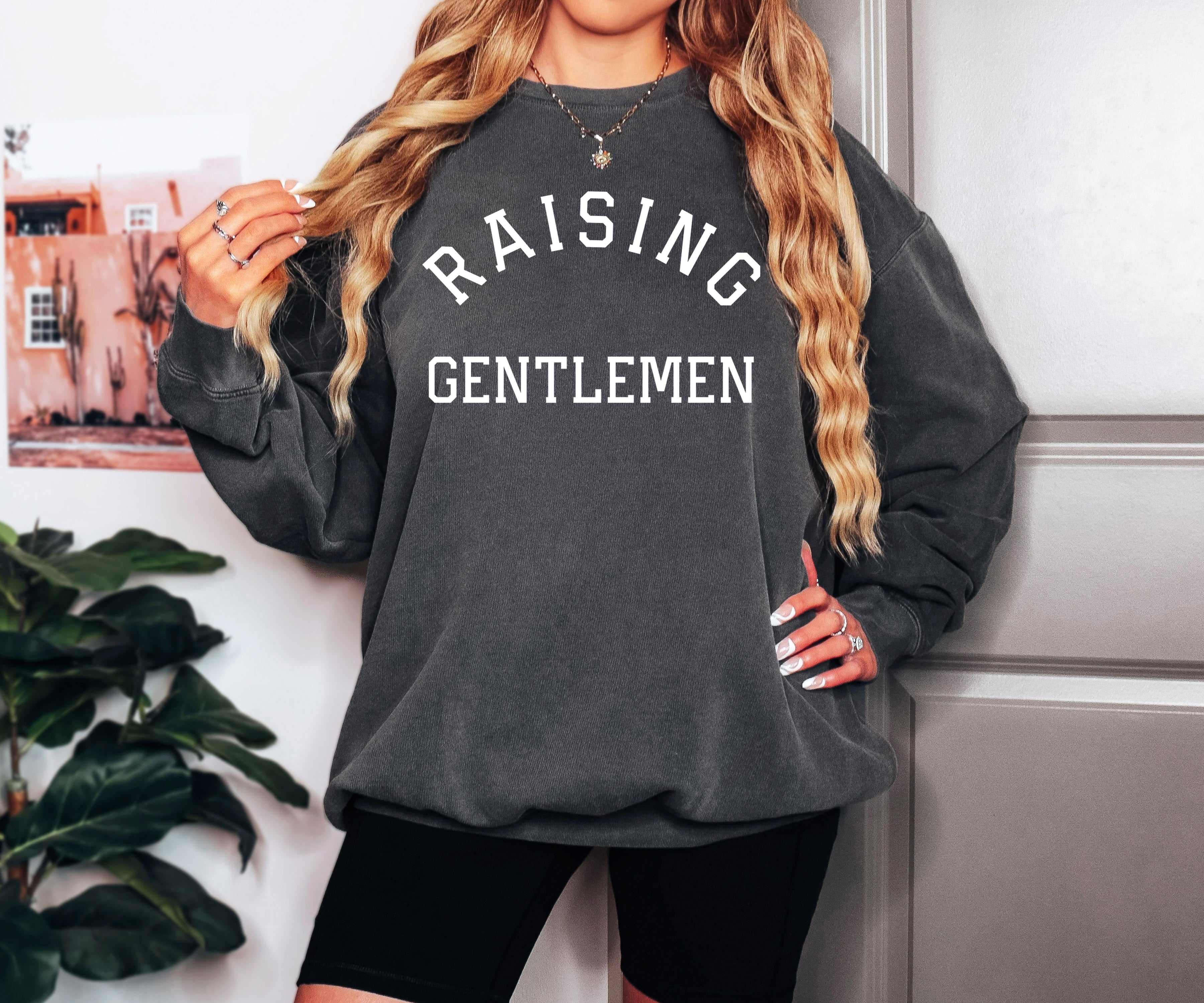 Black crewneck sweatshirt with "RAISING GENTLEMEN" text print