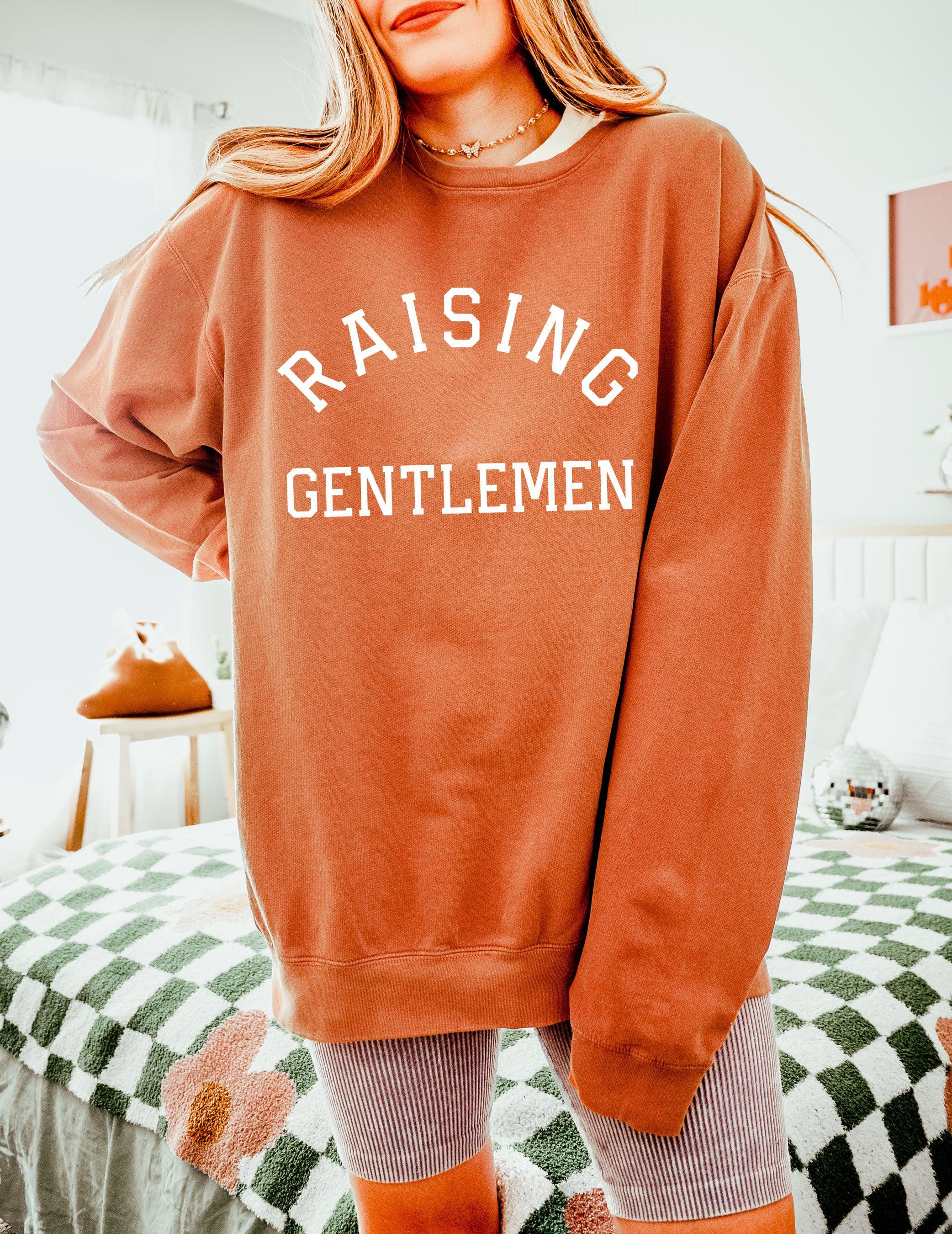 Rust brown crewneck sweatshirt with "RAISING GENTLEMEN" text print