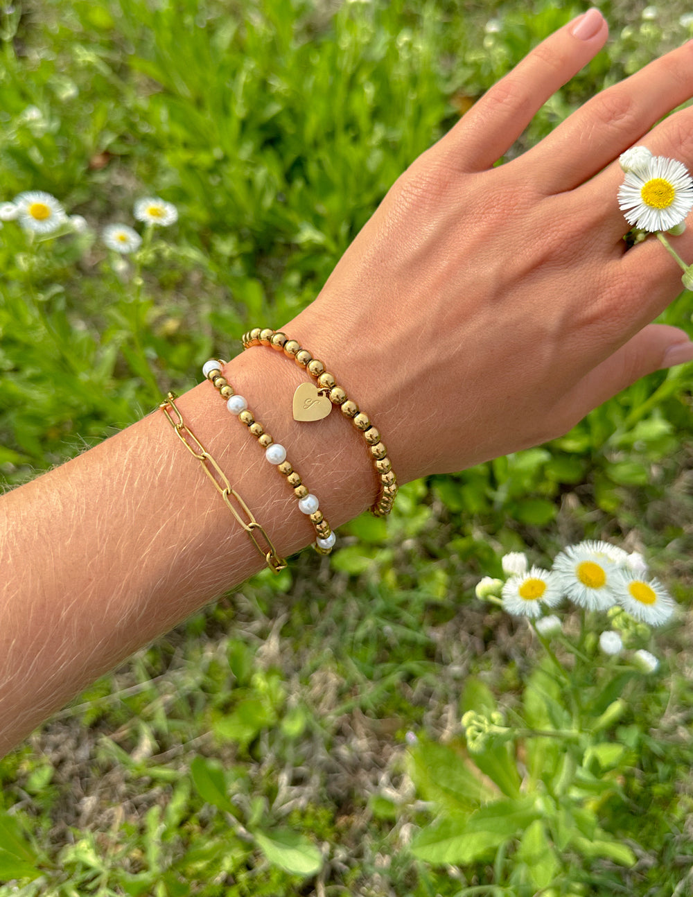 Gold-tone beaded bracelet pack with heart charm and white bead accents on wrist