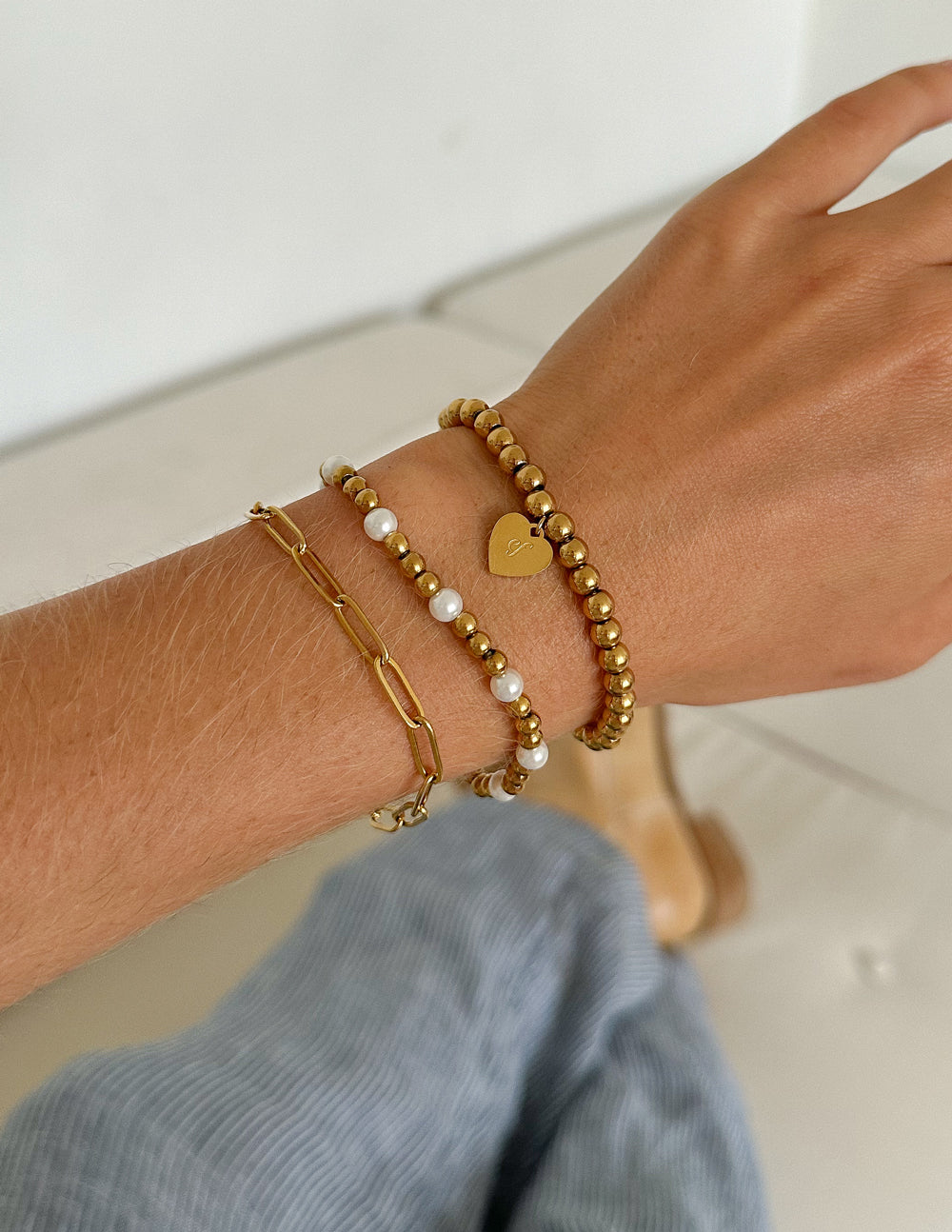 Stacked gold-tone beaded bracelets with heart charm and white bead accents