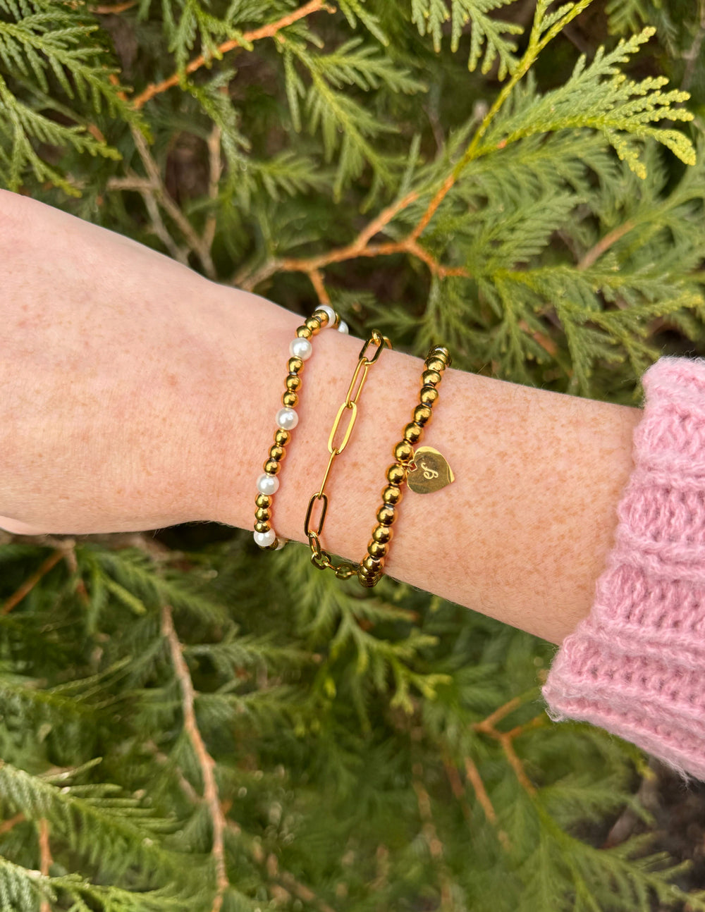 Gold-tone beaded bracelet set with heart charm, clasp link, and white beads