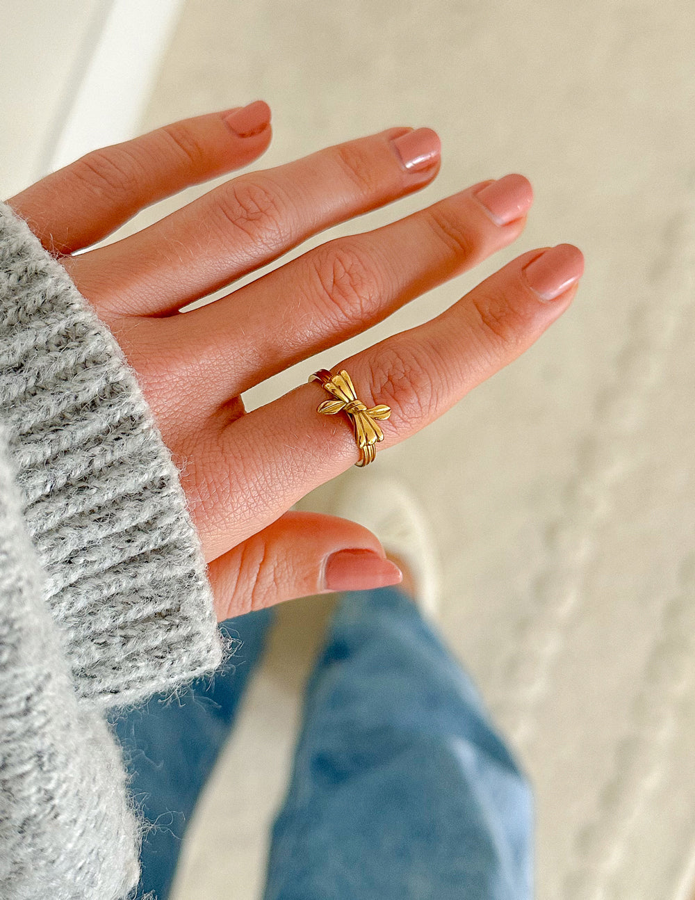 Gold ribbon bow ring on finger, bow knot at front