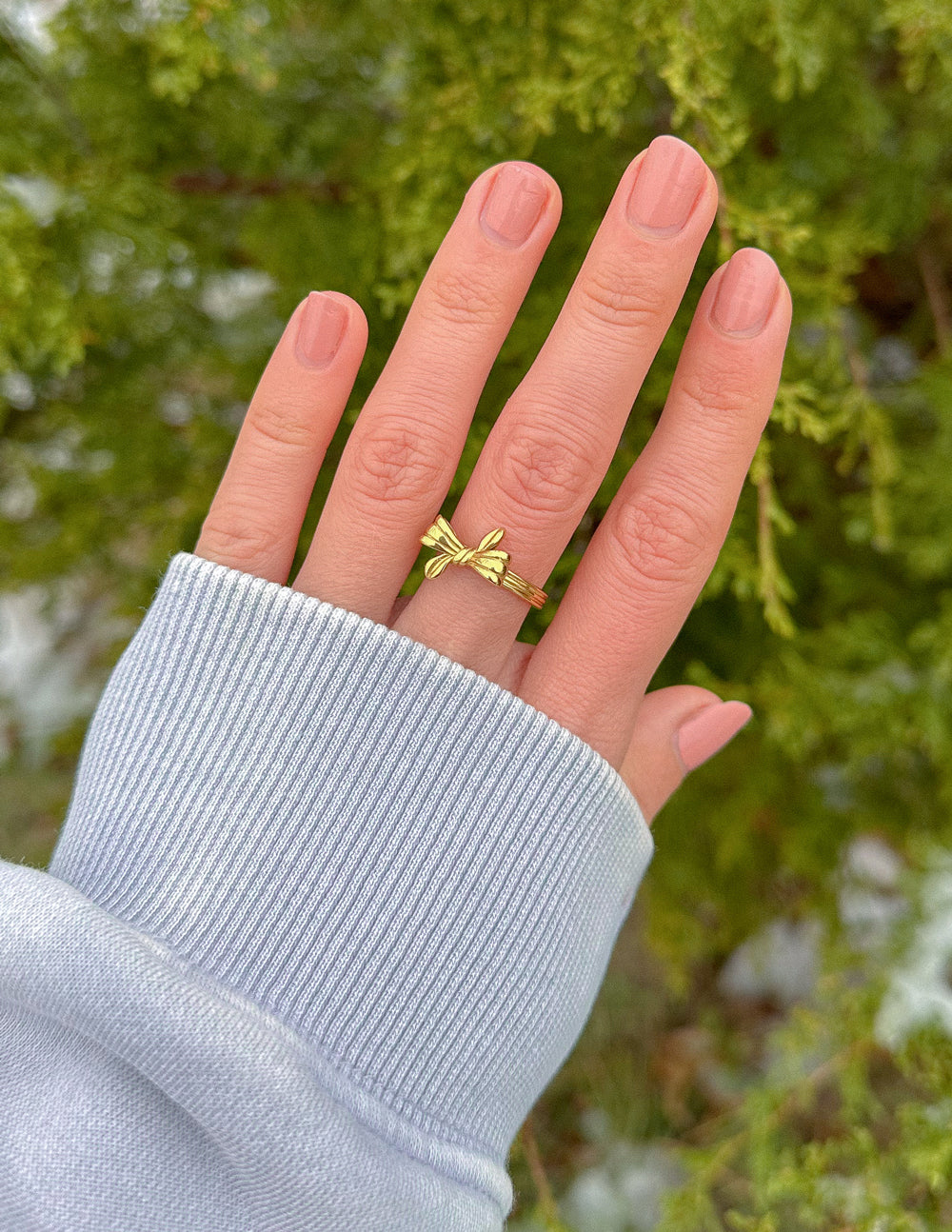 Gold bow ribbon ring on finger with two tied loops