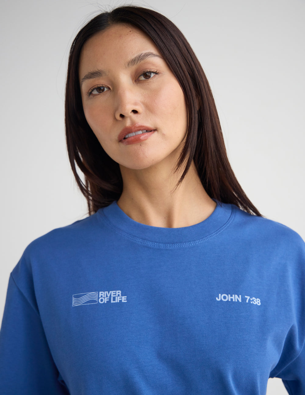 Blue crew-neck T-shirt with small River of Life flag logo and John 7:38