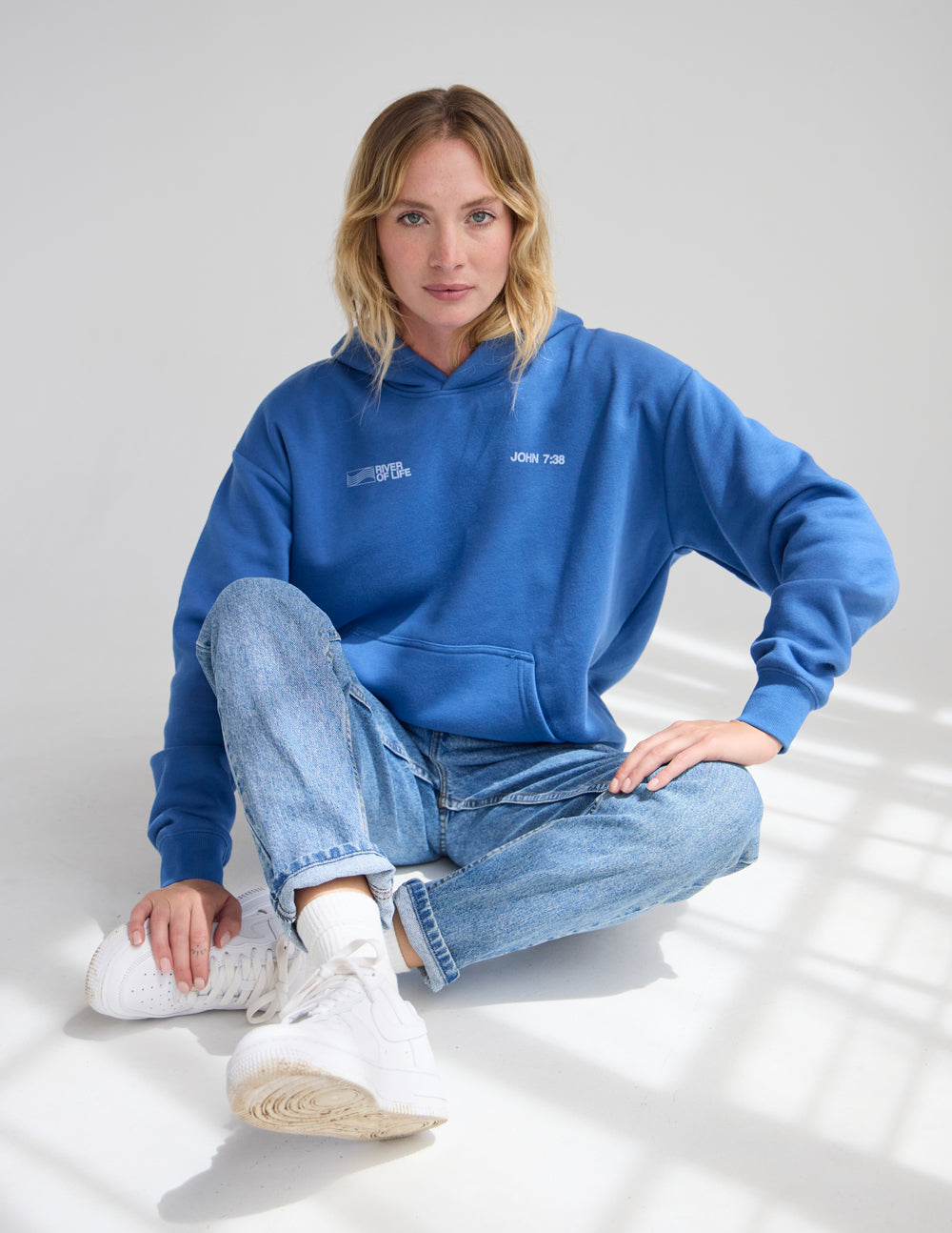 Blue unisex hoodie with hood and front pocket, chest logo text and graphic.