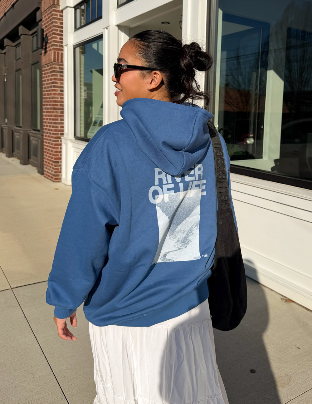 Blue hoodie back view with large “RIVER OF LIFE” print and hood.