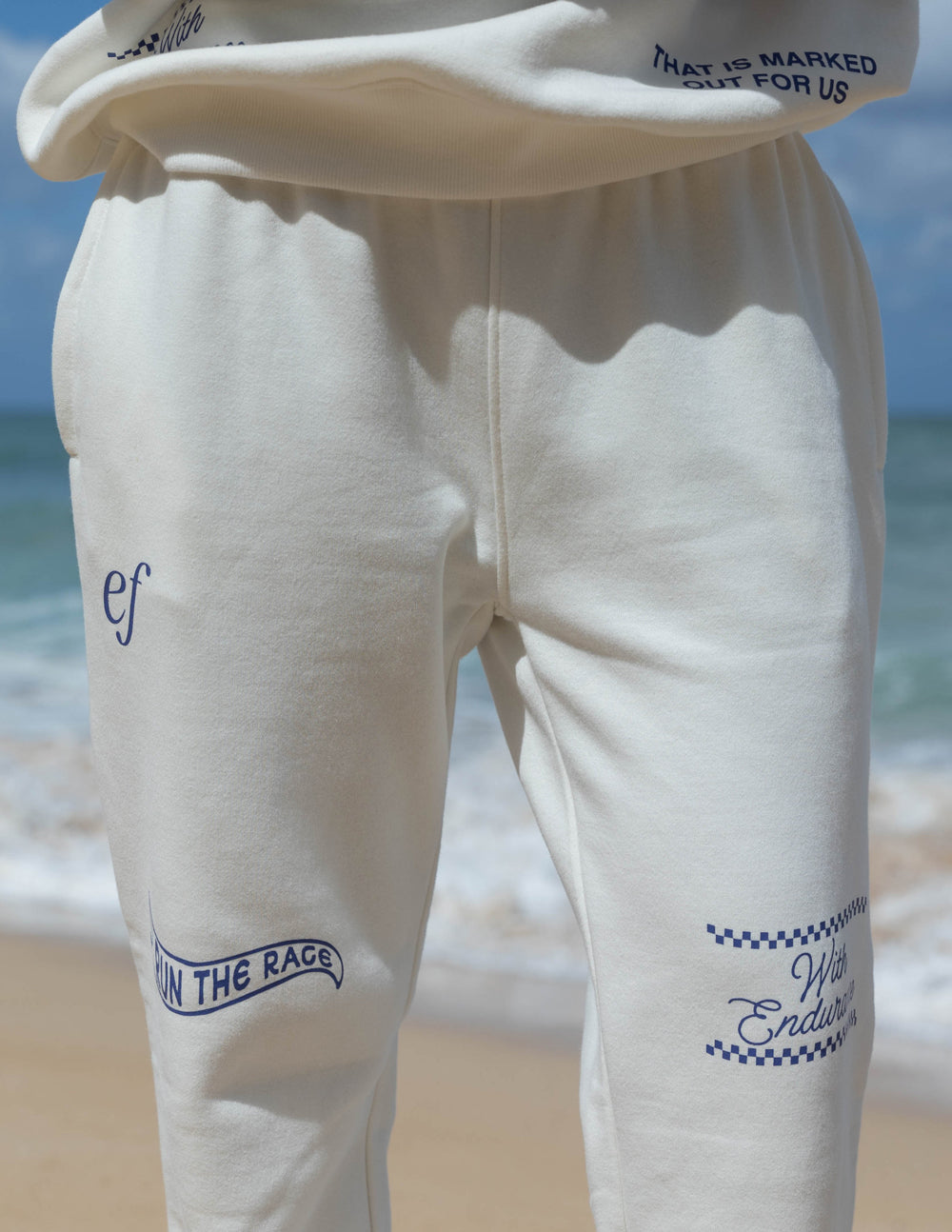 White sweatpants with blue logo on thigh and elastic waistband