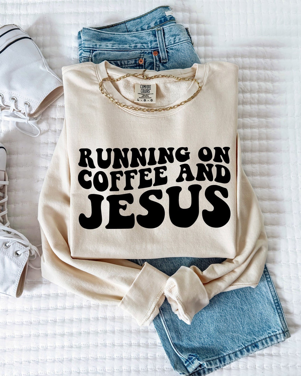 Ivory sweatshirt with bold "RUNNING ON COFFEE AND JESUS" text front.