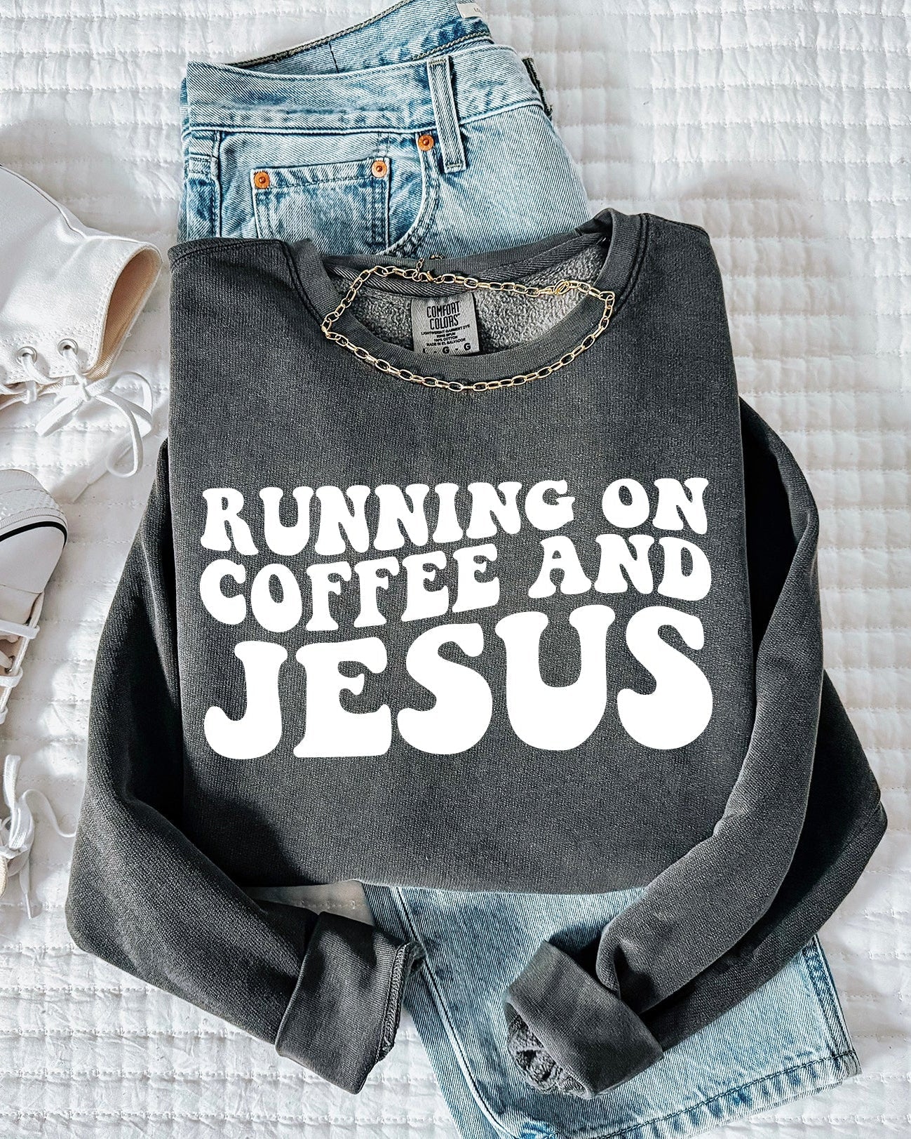 Charcoal dark sweatshirt with bold "RUNNING ON COFFEE AND JESUS" text front.