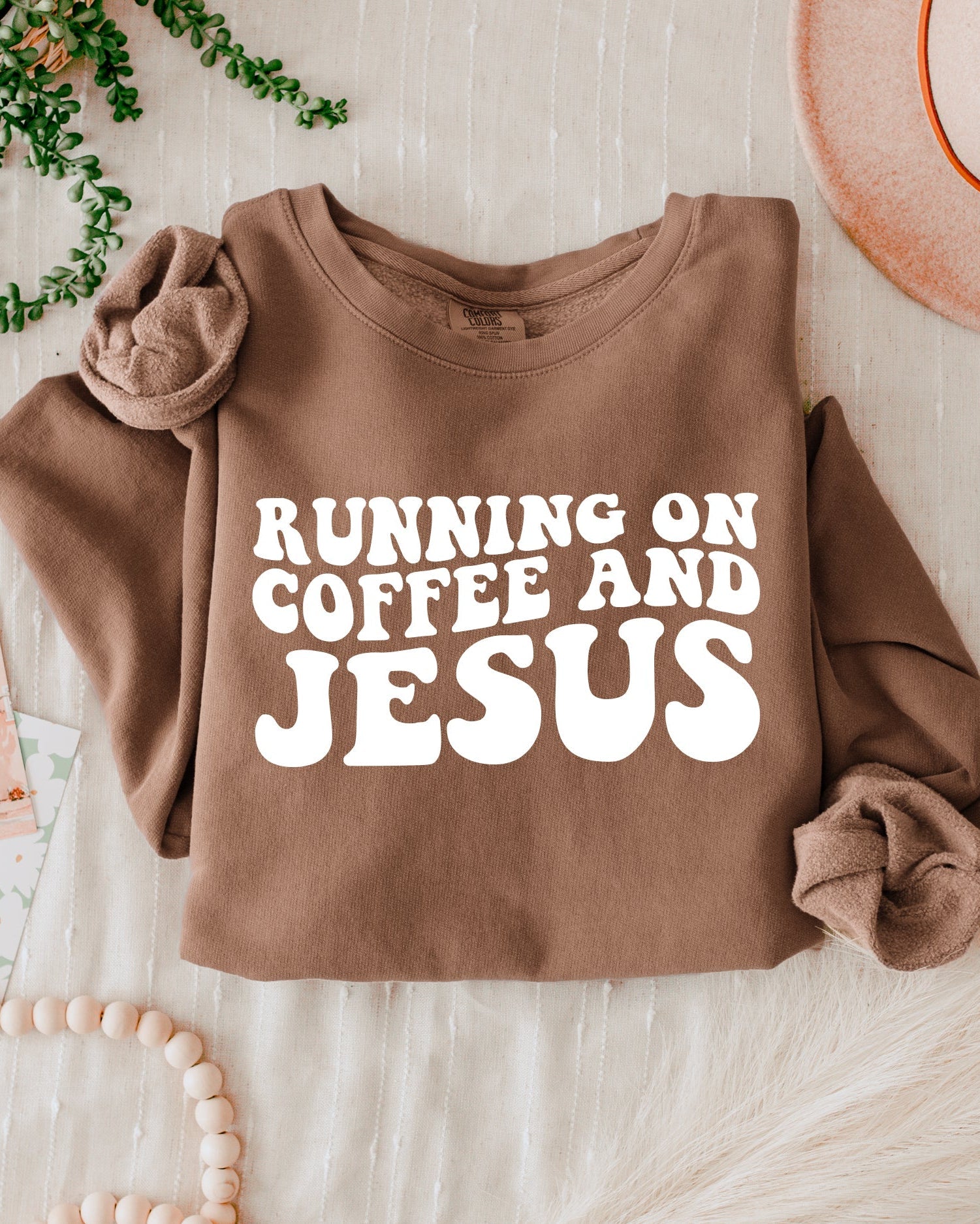 Espresso-brown sweatshirt with bold "RUNNING ON COFFEE AND JESUS" text front.
