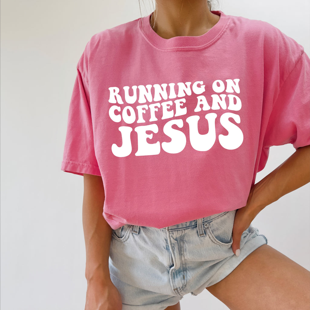 Pink graphic Christian T-shirt with “RUNNING ON COFFEE AND JESUS” text