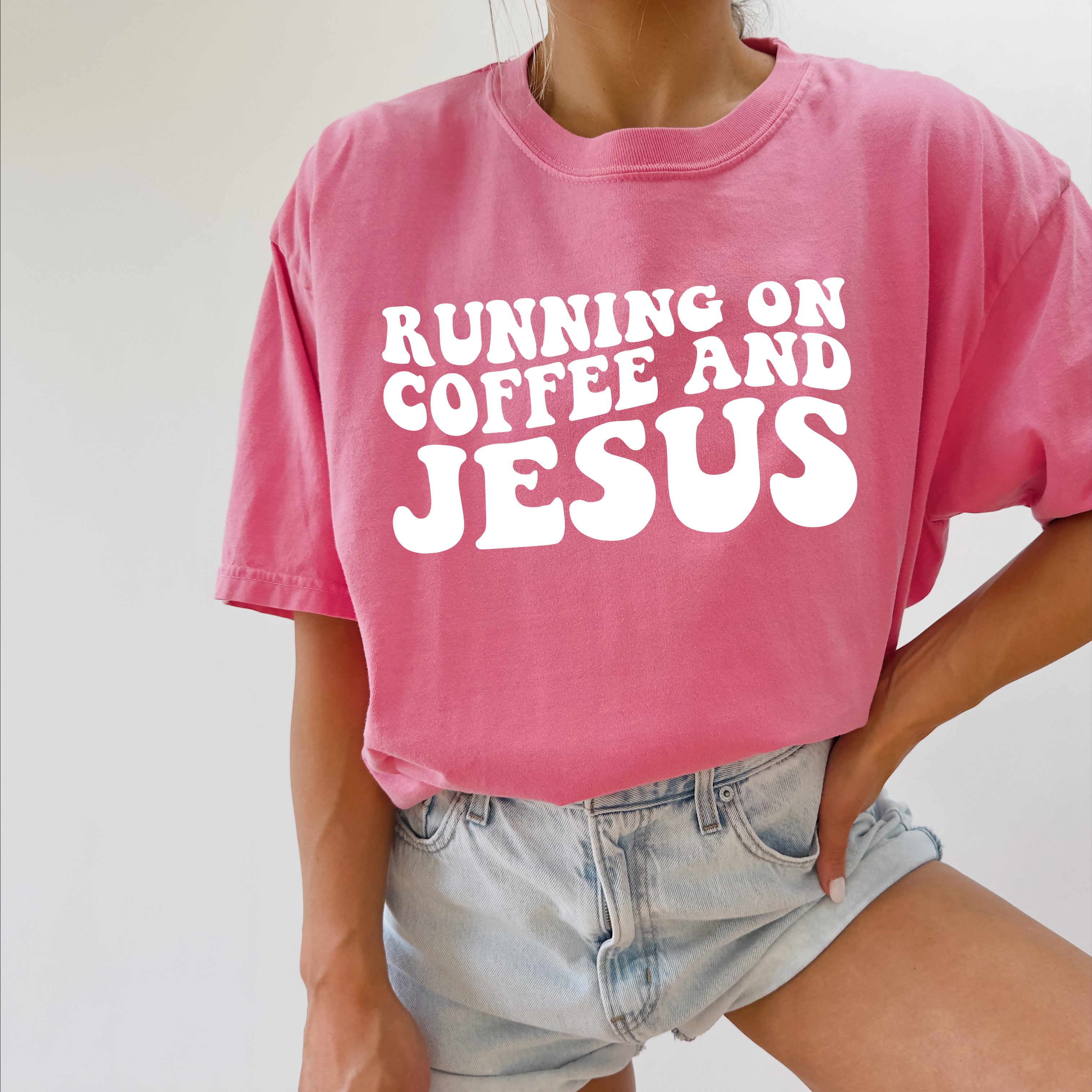 Pink graphic Christian T-shirt with “RUNNING ON COFFEE AND JESUS” text