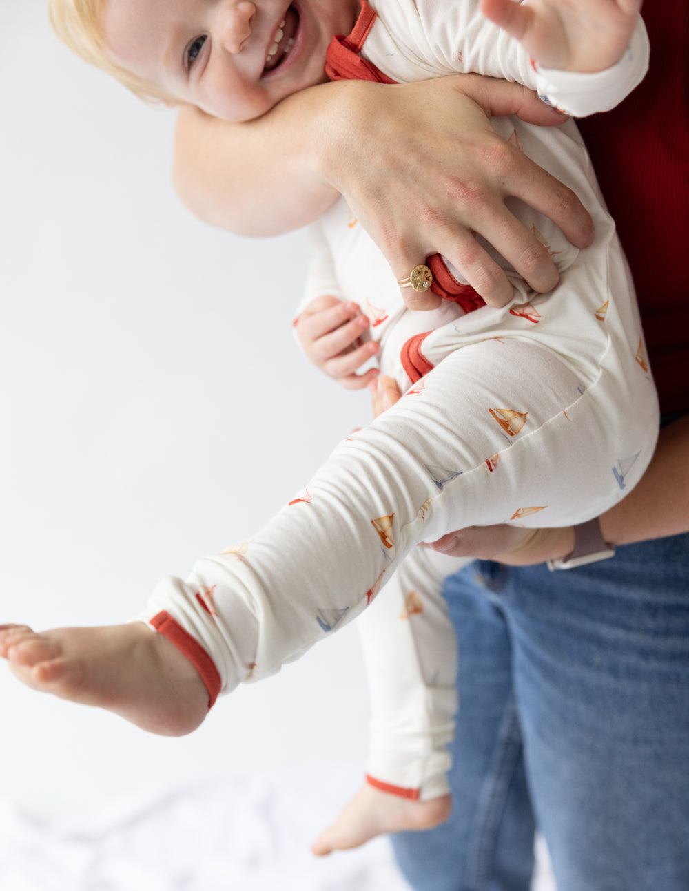 Footed onesie with sailboat print, red zip-front, rolled cuffs, shown in side view