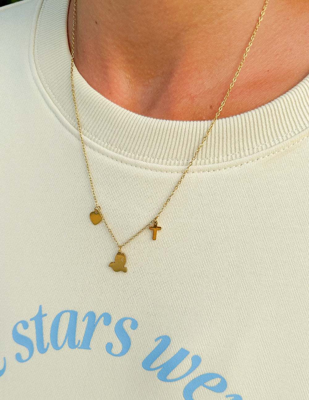 Gold-tone charm necklace with heart and cross charms and a small dove charm