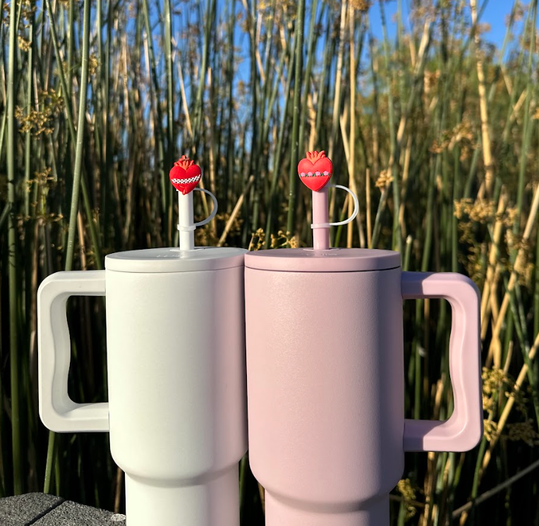 Two red heart straw toppers with crown and loops on straws from matching insulated cups