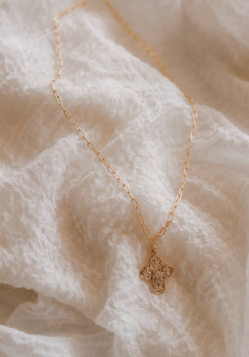 Gold four-way cross pendant necklace on paperclip chain, angled view