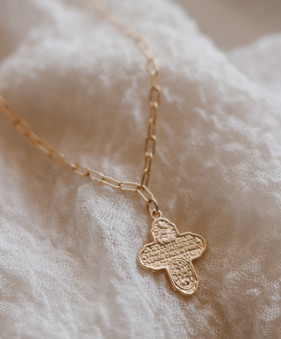 Gold four-way cross pendant on paperclip chain, close-up