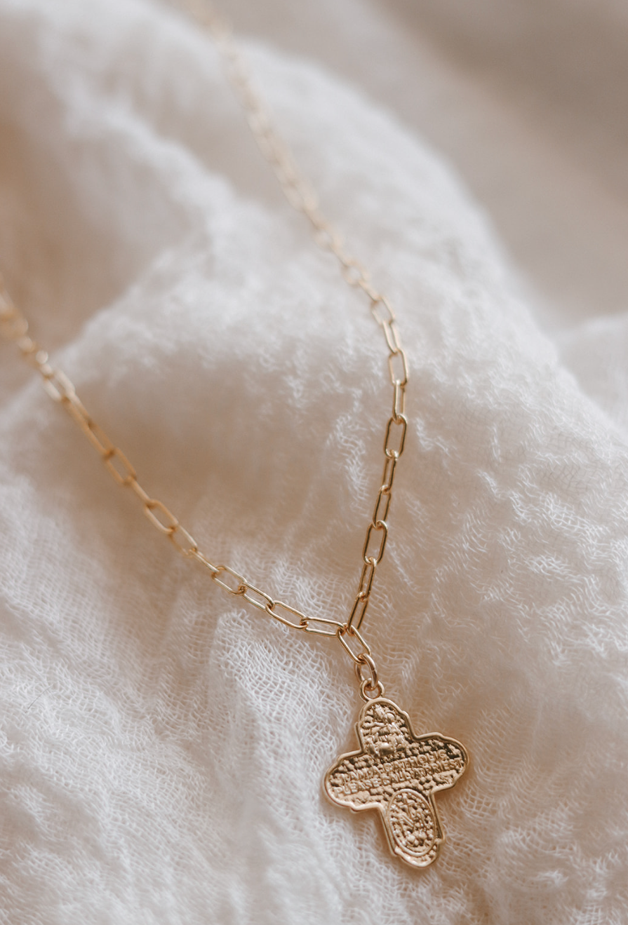 Gold four-way cross pendant necklace on paperclip chain, close-up detail