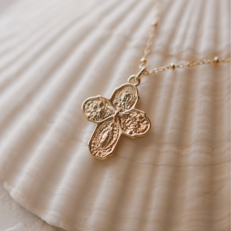 Gold-tone cross pendant necklace with delicate chain, angled pendant close-up.