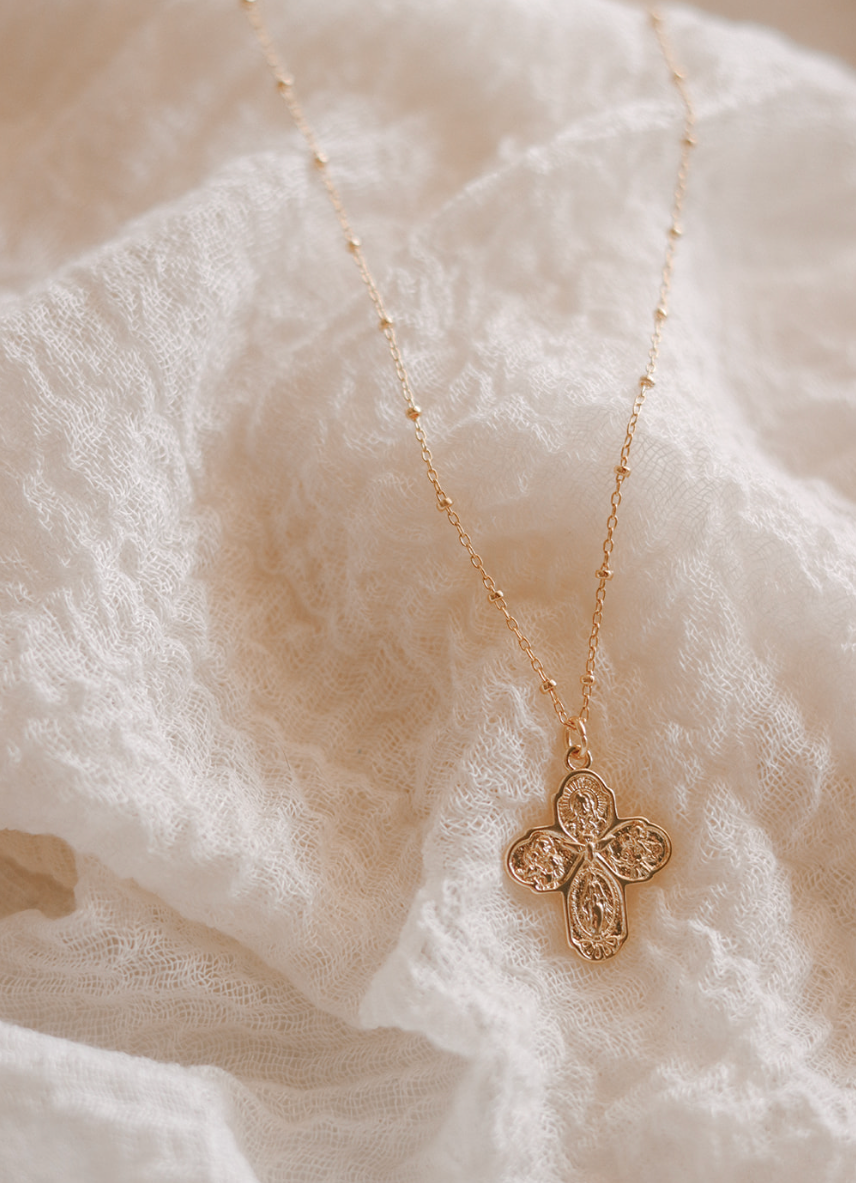 Gold cross necklace with textured filigree cross pendant on a fine chain