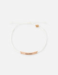 White cord bracelet with gold beads and a "Seek Him" metal charm