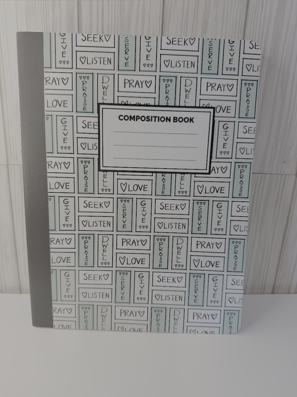 Green composition book with prayer-themed typographic cover and ruled writing lines