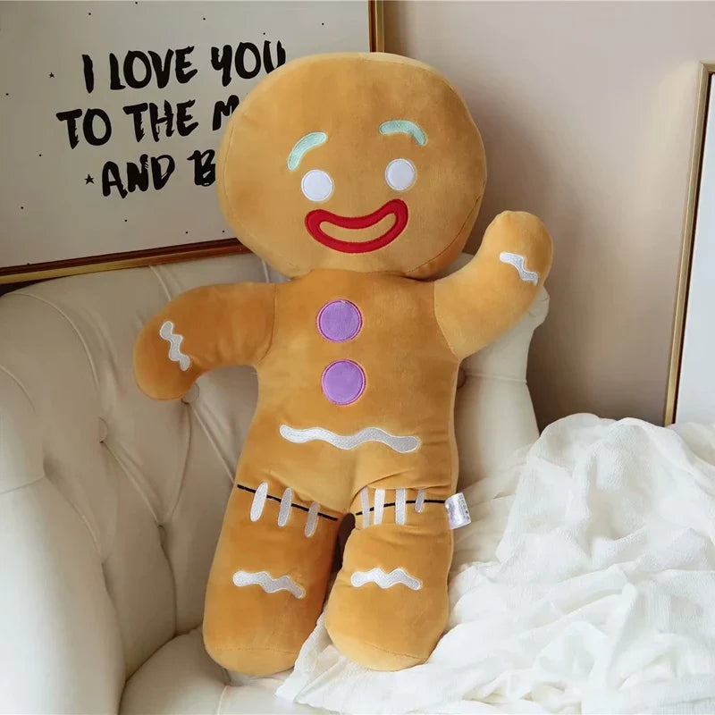 Full-body gingerbread man plush toy with red smile, purple buttons, and white icing laces on pants.